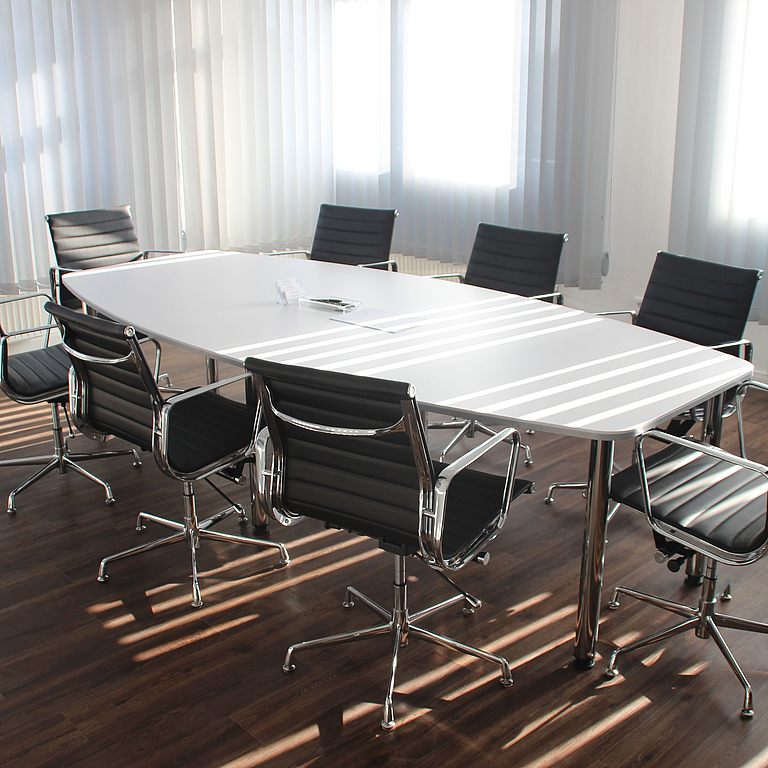 Sitzungsraum mit einem langen Tisch und mehreren Stühlen
